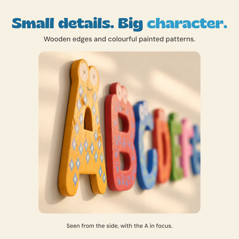 Close side view of wooden magnetic letters on a warm ivory surface, showing their thickness and painted details.