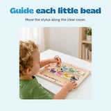 The existing source child using the wooden stylus to guide a bead on the monster sorting board.