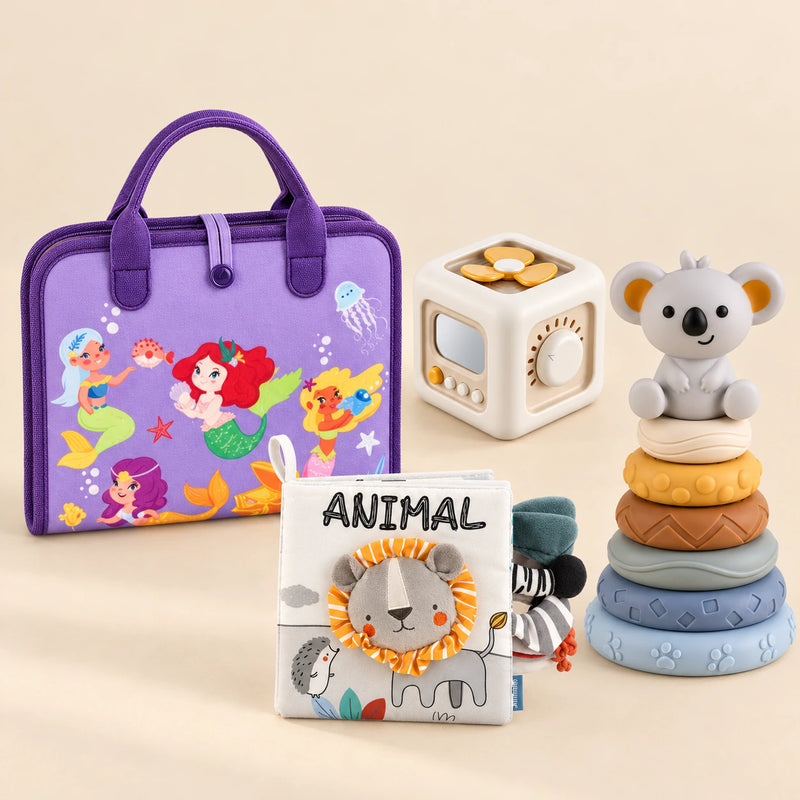 Mermaid Purple Plus busy board with an off-white and yellow activity cube, ANIMAL lion cloth book and six-ring koala stacking tower on a calm beige background.