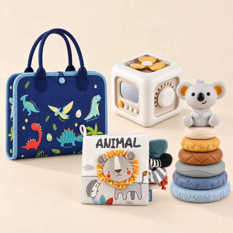 Dinosaur Blue Plus busy board with an off-white and yellow activity cube, ANIMAL lion cloth book and six-ring koala stacking tower on a calm beige background.