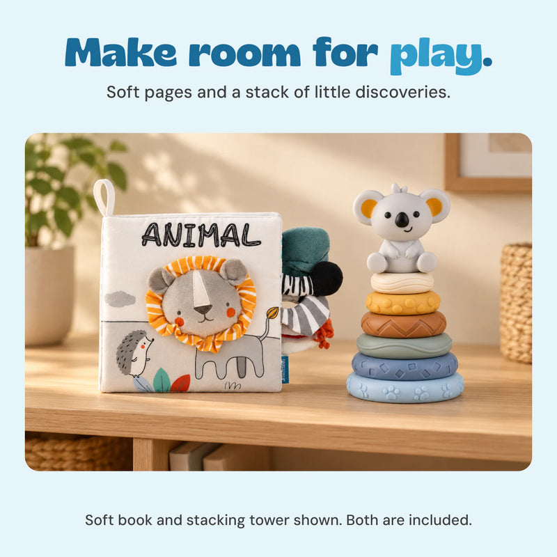 The ANIMAL lion cloth book and six-ring koala stacking tower stand together on a calm wooden shelf.