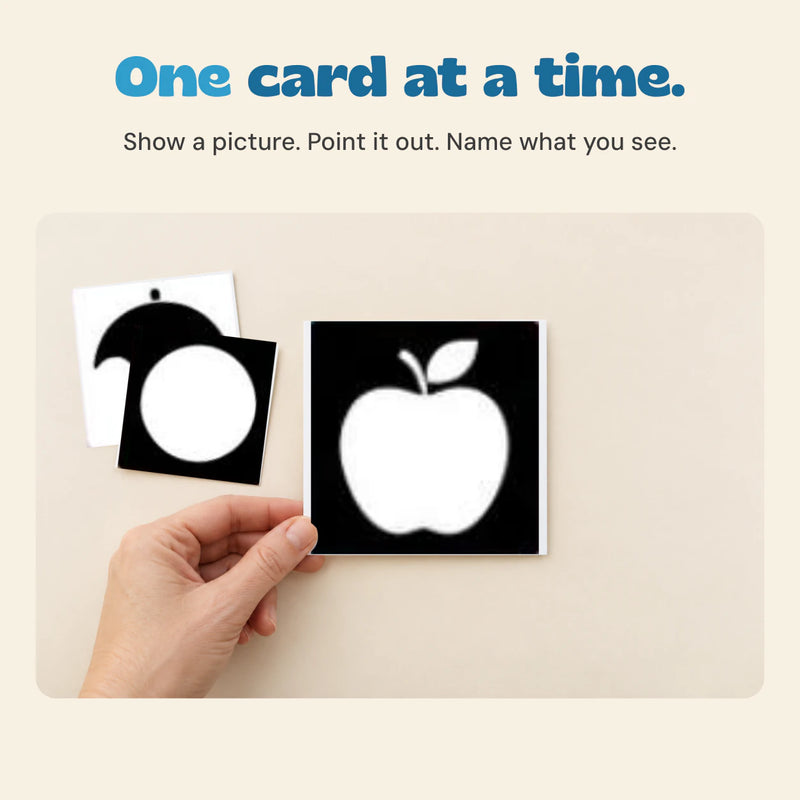 Adult hand holding the original black-and-white apple card, with umbrella and circle cards nearby.