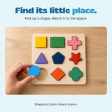 An adult hand places the blue circle above its empty circular recess on the Shapes & Colors Board.