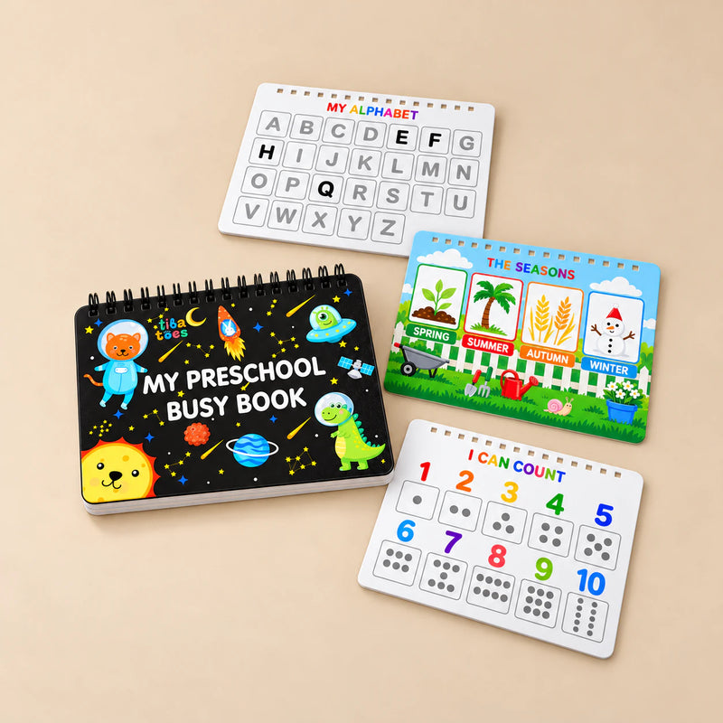 Black TibaToes Preschool Busy Book with alphabet, seasons and counting page previews arranged on a warm beige studio surface