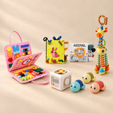 No-Screen Starter Kit Bundle with its matching busy board, cloth books, busy cube, giraffe rattle and three turtle toys on a warm beige studio surface.