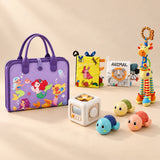No-Screen Starter Kit Bundle with its matching busy board, cloth books, busy cube, giraffe rattle and three turtle toys on a warm beige studio surface.