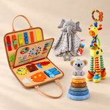 Calm and Focus Bundle with an orange animal busy board, grey elephant comforter, giraffe rattle and six-ring koala stacking tower on a warm beige studio floor.