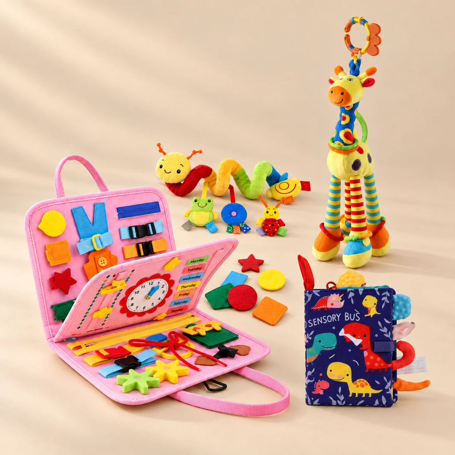 Sensory Explorer Bundle with pink busy board and loose felt shapes, dinosaur sensory book, giraffe rattle and spiral stroller toy on a beige studio floor.
