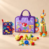 Sensory Explorer Bundle with a purple mermaid busy board, dinosaur cloth book, giraffe rattle and spiral stroller toy on a warm beige studio floor.