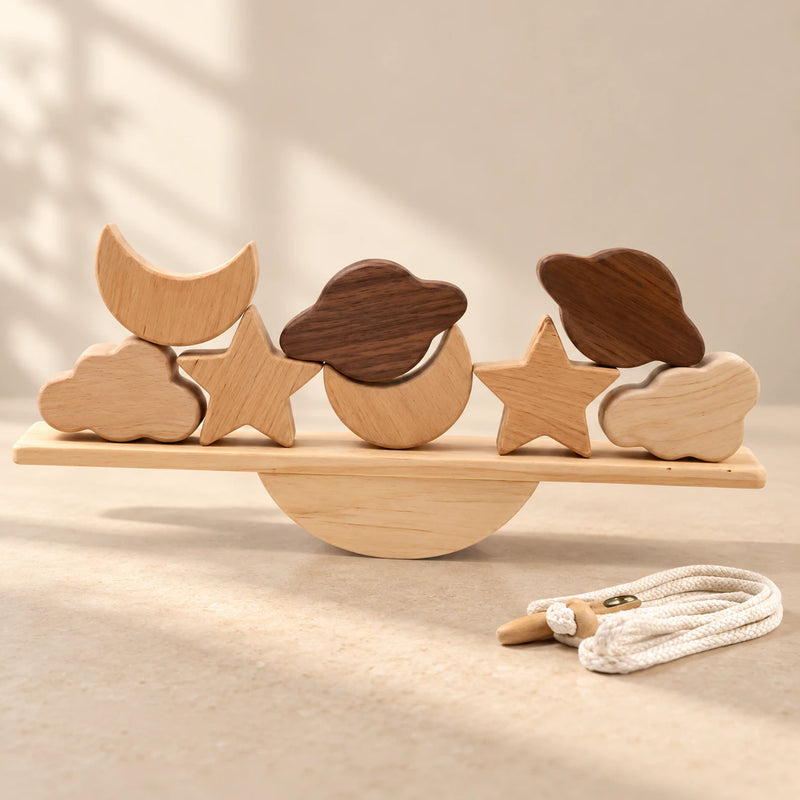 Two moons, two stars, two clouds and two planet-shaped pieces on a straight wooden balance plank, with a semicircular rocker and threading cord.
