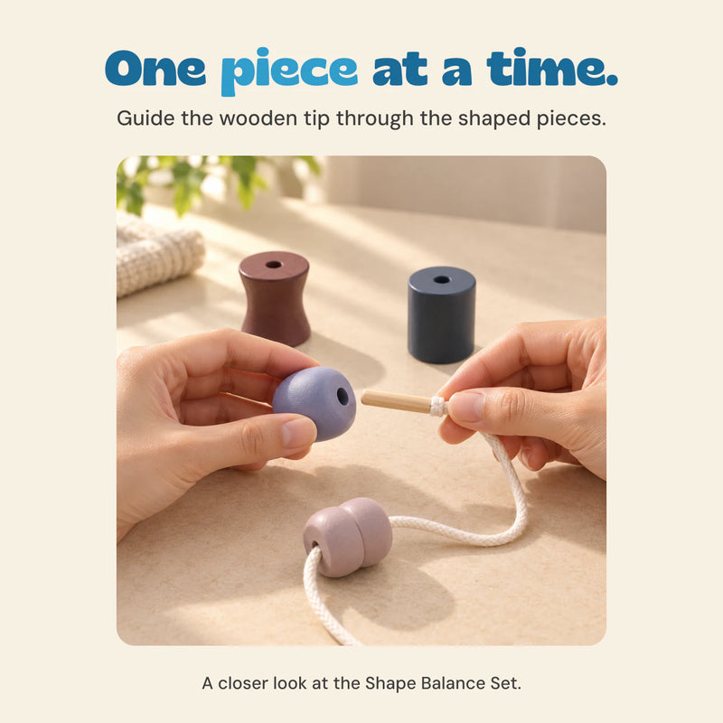 Two adult hands guide the wooden threading tip toward a lilac wooden shape, with a second shape already on the cotton cord.
