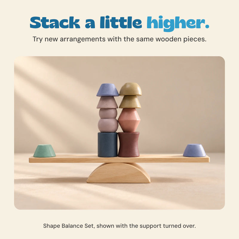 Two columns of geometric wooden pieces stacked on a plank supported by the semicircular base turned flat-side down.