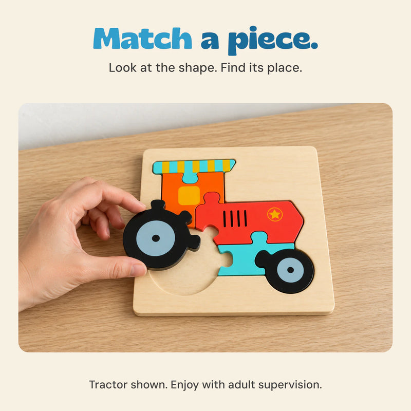 An adult hand matches the large rear wheel piece to the wooden Tractor puzzle on a pale oak table.