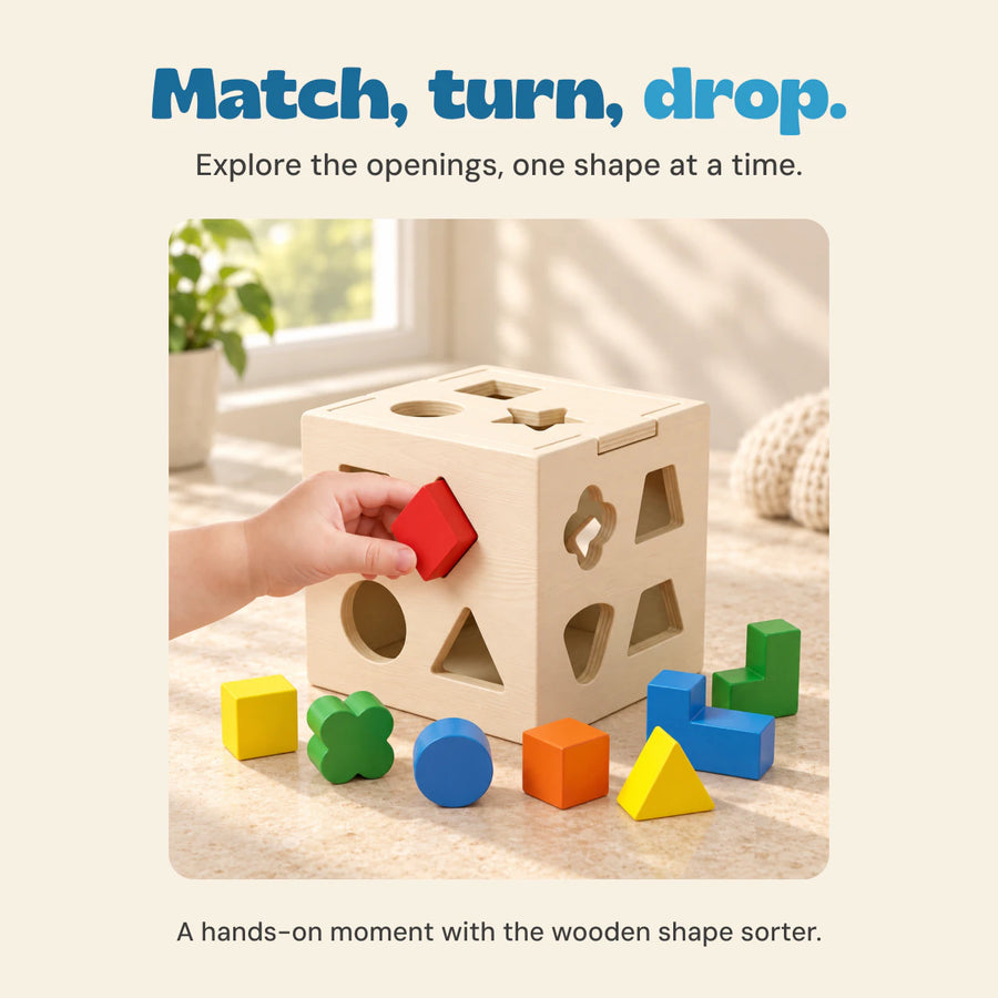 A hand turns a red wooden shape toward the cube, with colourful sorting pieces on the table.