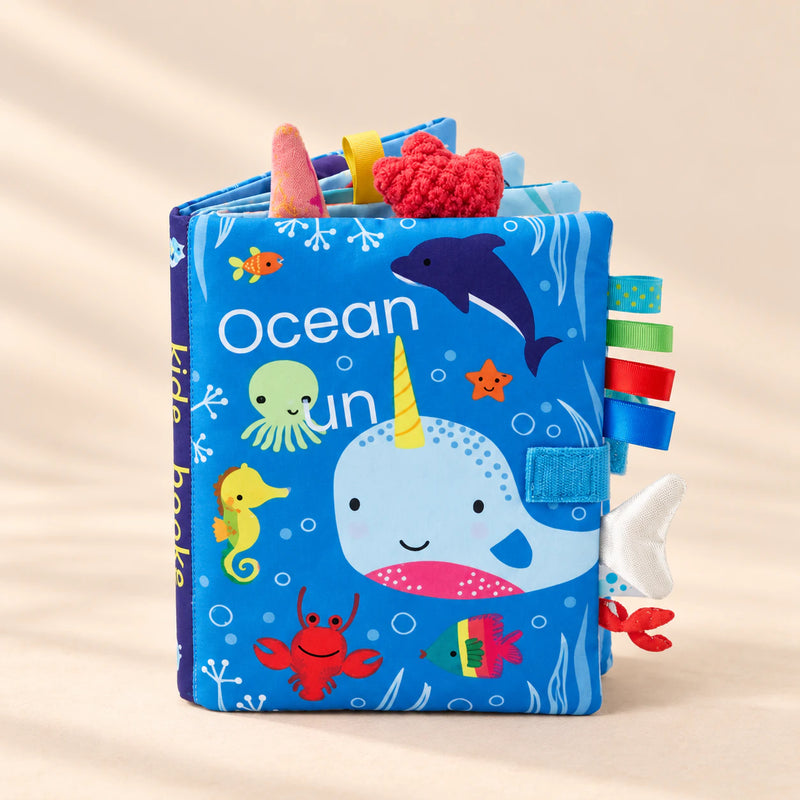 TibaToes Snuggle Stories Ocean Fun cloth sensory book on a warm beige background.