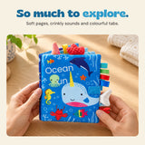 Hands holding the Ocean Fun sensory book, with soft pages, crinkly sounds and colourful tabs.