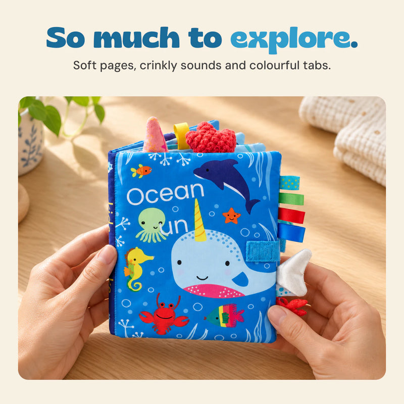 Hands holding the Ocean Fun sensory book, with soft pages, crinkly sounds and colourful tabs.