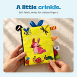 Hands gently handling the soft Garden Fun sensory book on linen.
