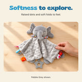 An adult hand touches the raised-dot grey fabric of the elephant comfort blanket on a wooden table.