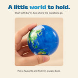 An adult hand holding the Earth ball, with an idea to find the matching planet in a space book.