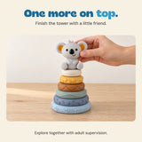 An adult hand steadies the koala topper on the complete six-ring tower.