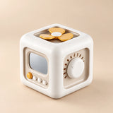 TibaToes Montessori Busy Cube in Off White/Yellow, showing its visible activity panels on a warm beige background.