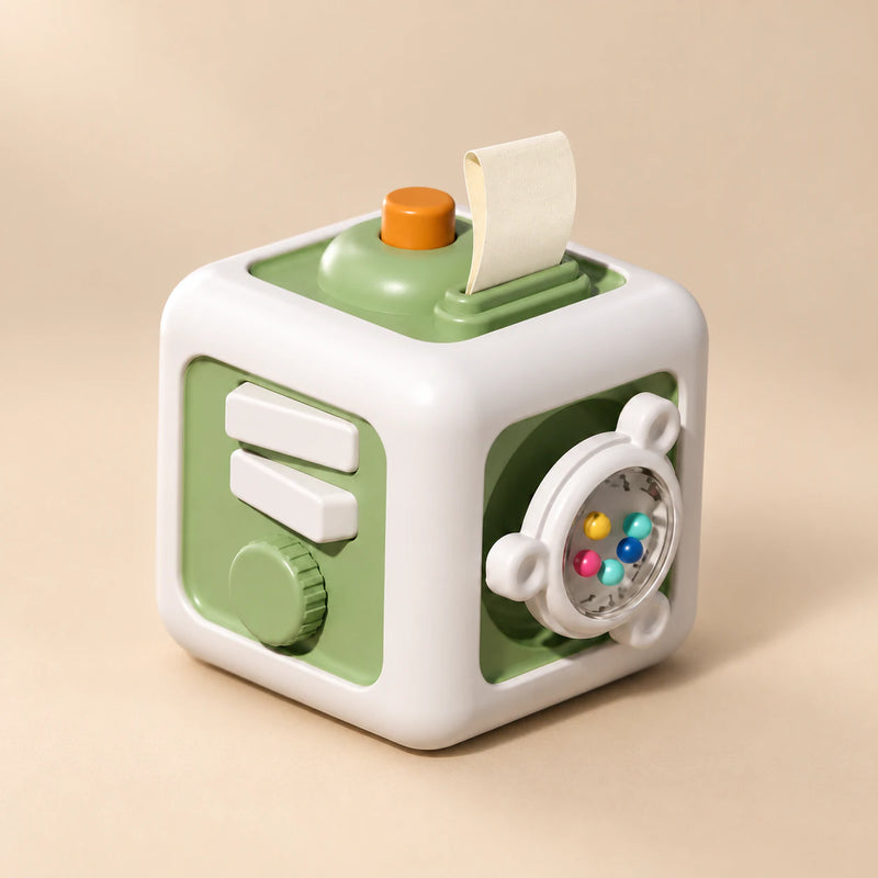 TibaToes Montessori Busy Cube in Green/White, showing its visible activity panels on a warm beige background.