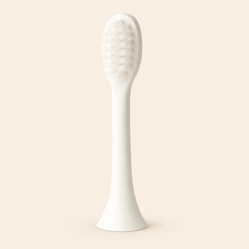 One ivory-white replacement brush attachment with an oval bristle head, slender stem and flared connector, shown alone on warm beige.