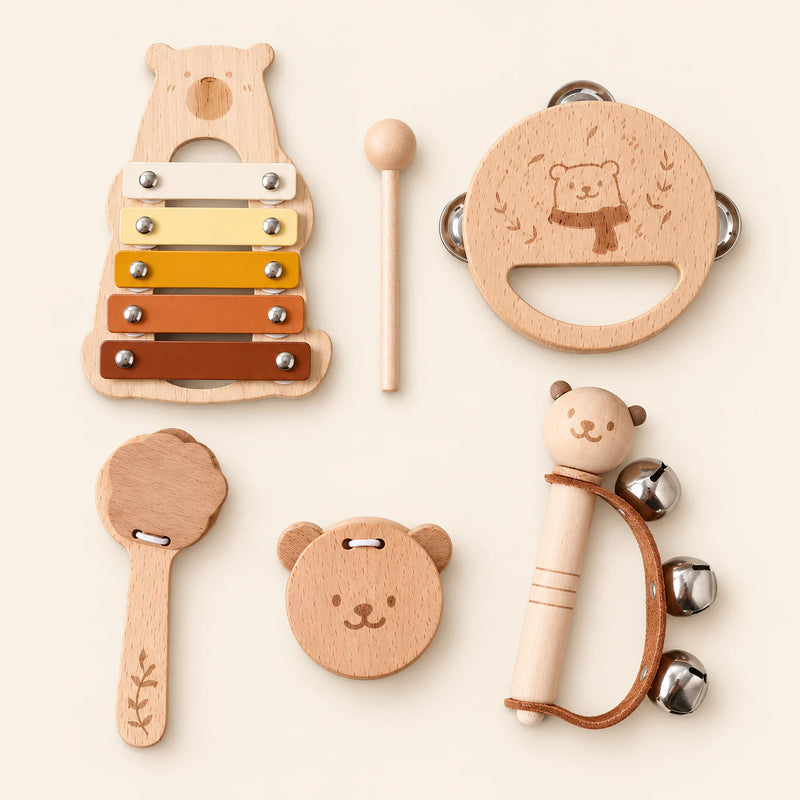 Five wooden bear instruments and one mallet: a five-bar xylophone, tambourine, clapper, castanet and bell rattle on warm beige.