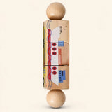 Wheel & Whirl wooden Spin and Match toy with three connected rotating blocks and two wooden ball ends, showing one printed face on smooth pale warm beige.