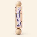 Puppy Pals & Friends wooden Spin and Match toy with three connected rotating blocks and two wooden ball ends, showing one printed face on smooth pale warm beige.