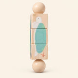 Ocean Spin wooden Spin and Match toy with three connected rotating blocks and two wooden ball ends, showing one printed face on smooth pale warm beige.
