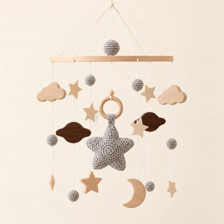 Grey hanging mobile with its source-matched wooden support, cords and individual charms on warm beige.