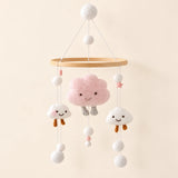 Pink Cloud Plush hanging mobile with its source-matched wooden support, cords and individual charms on warm beige.