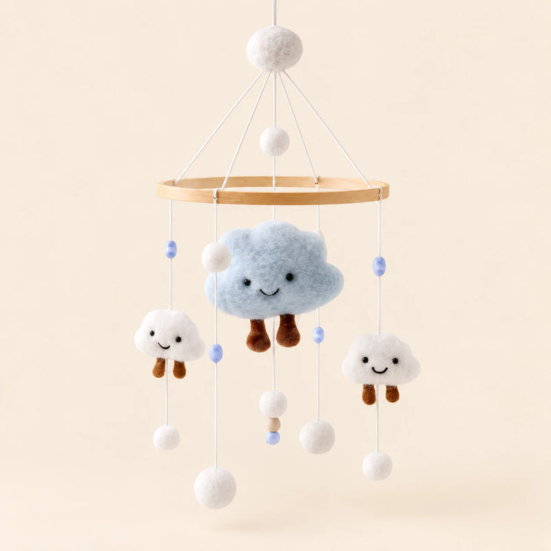 Blue Cloud Plush hanging mobile with its source-matched wooden support, cords and individual charms on warm beige.