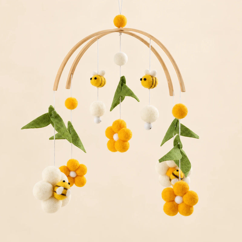Yellow Honey Bee hanging mobile with its source-matched wooden support, cords and individual charms on warm beige.