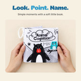 Two adult hands hold the Animal Cognition soft cloth book, keeping the illustrated bear and owl cover visible.