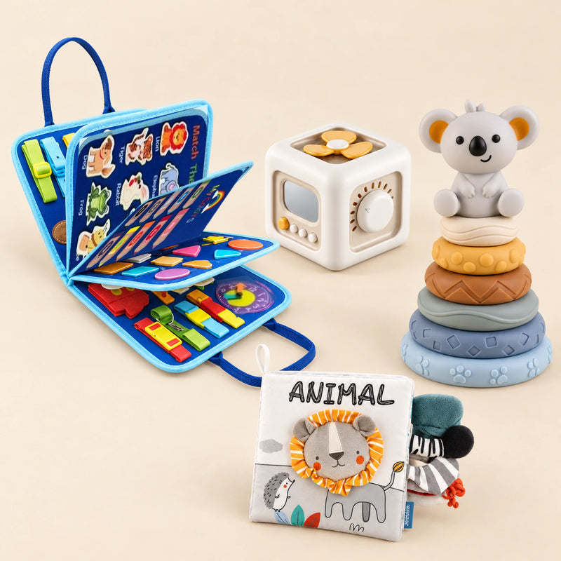 Vehicle Blue Plus busy board with an off-white and yellow activity cube, ANIMAL lion cloth book and six-ring koala stacking tower on a calm beige background.
