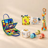 No-Screen Starter Kit with the Dinosaur Blue busy board, two soft books, giraffe rattle, busy cube and three turtles, arranged in a warm beige studio.