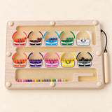 Wooden magnetic sorting board with ten colourful monster cups, beads and an attached wooden stylus on warm beige.