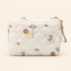 Cream quilted zip pouch with animal print, top zipper and snap wrist loop, on warm beige.