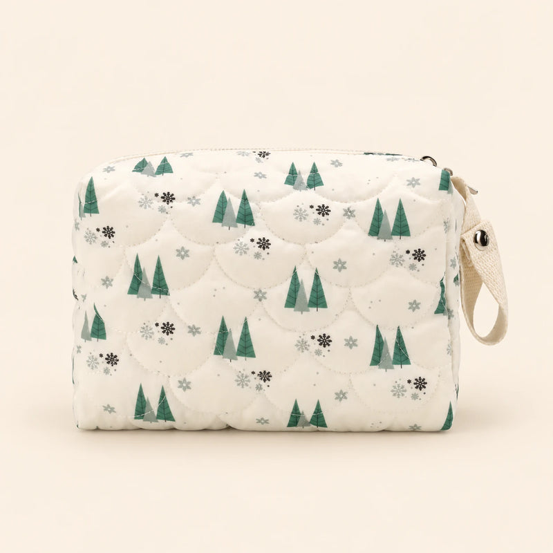 Cream quilted zip pouch with tree print, top zipper and snap wrist loop, on warm beige.