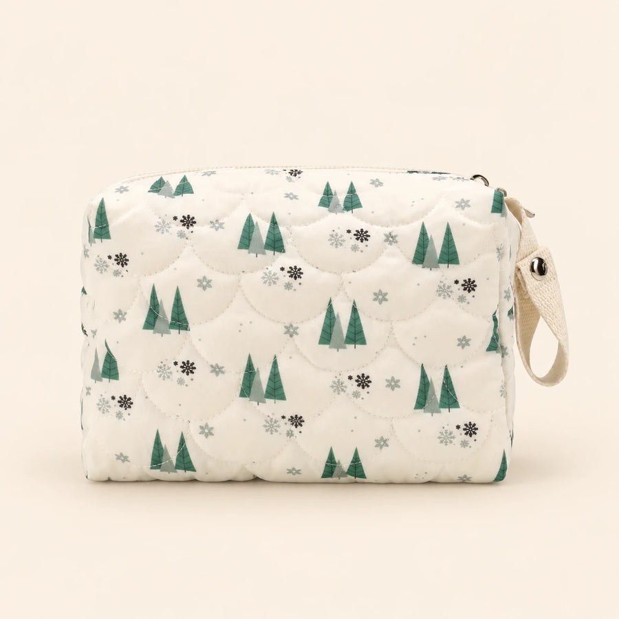 Cream quilted zip pouch with tree print, top zipper and snap wrist loop, on warm beige.