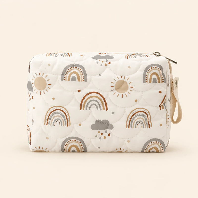 Cream quilted zip pouch with rainbow print, top zipper and snap wrist loop, on warm beige.