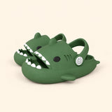 A matching pair of shark slides in the Dark Green colour on a warm beige background.