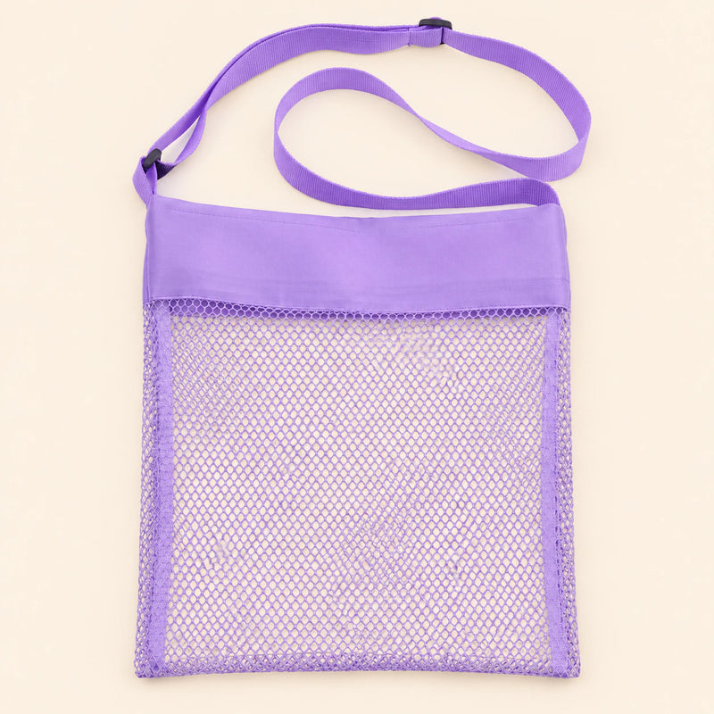 Purple Splash mesh beach bag shown empty, with matching adjustable shoulder strap and black slider on smooth pale warm beige.