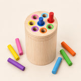 Natural wooden sorting cylinder with eight colour-rimmed holes and colourful rods on warm beige.