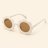 One pair of flower-shaped sunglasses with round brown lenses in the White colour on a warm beige background.