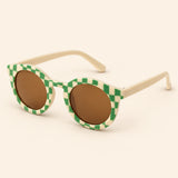 Green Checker Sun Shades with the original frame pattern, open arms and brown lenses on warm beige.