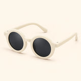 One pair of round sunglasses in the Cream White option on a warm beige background.